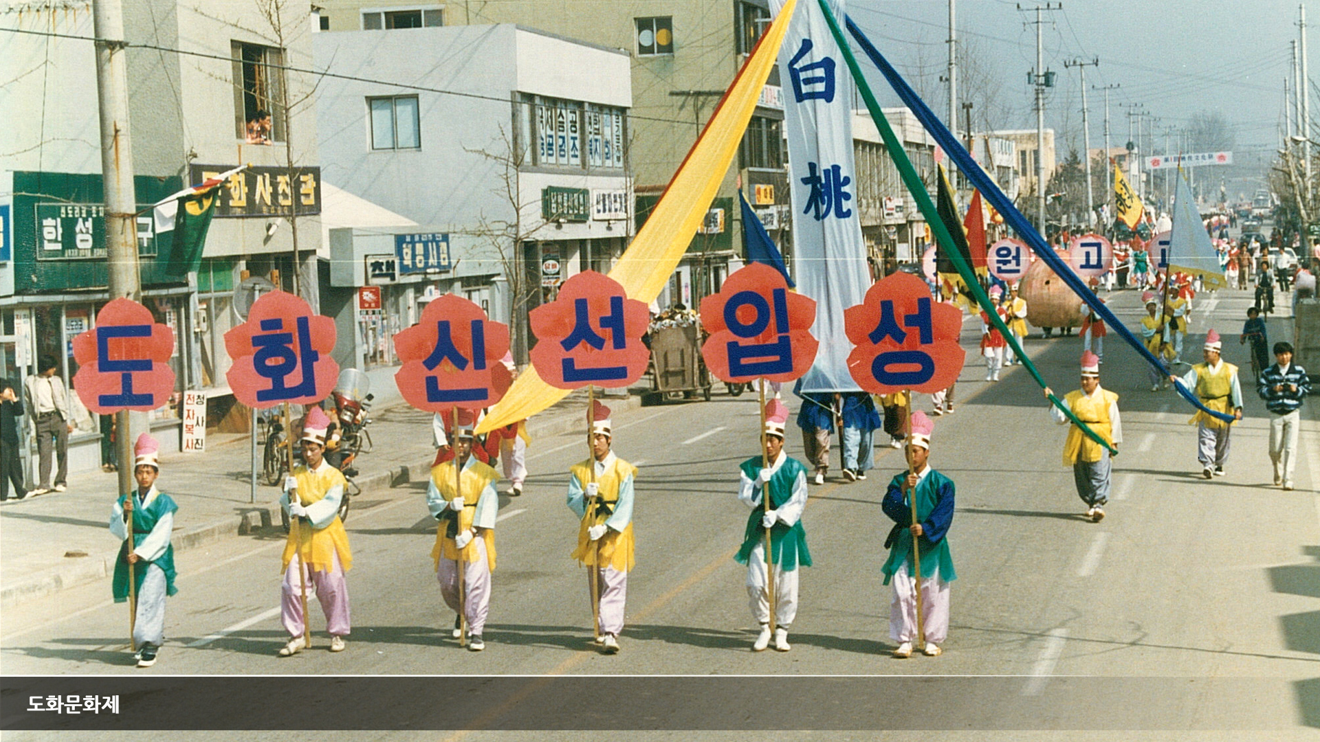 도화신선입성 이라는 팻말을 한글자 씩들고 전통 복장을 입은 남자들이 행진한다.